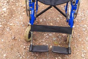 Empty wheelchair standing on road waiting for patient services. Wheel chair for people person with disability parked outdoor. Accessible for person with disability. Health care medical concept. photo