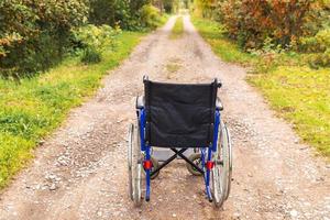 Empty wheelchair standing on road waiting for patient services. Wheel chair for people person with disability parked outdoor. Accessible for person with disability. Health care medical concept. photo