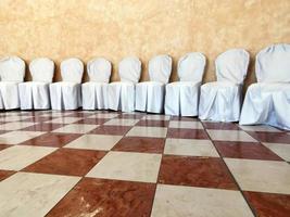 muchas sillas cubiertas de blanco para bodas foto