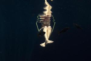Mujer de piernas hermosas bajo el agua en columpio de balancín foto