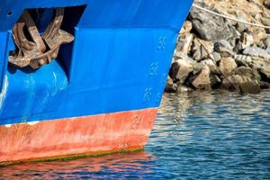 Rusted rugged Anchor on blue fishing ship photo