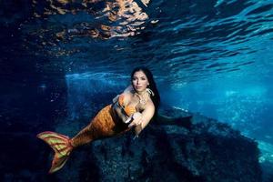 Mermaid swimming underwater in the deep blue sea photo