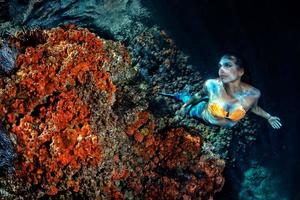 Mermaid swimming underwater in the deep blue sea photo