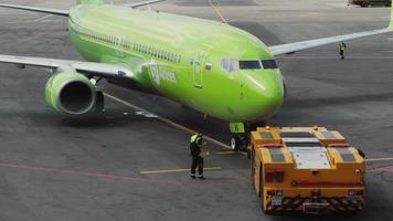 MOSCOW, RUSSIAN FEDERATION JULY 24, 2021 - Passenger Boeing 737 of S7 airlines pulls a tractor from the terminal in the international airport Domodevo, Moscow. Tourism and travel concept video