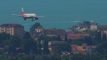 SOCHI, RUSSIA JULY 30, 2022 - Long shot, jet passenger plane Airbus A320 of Rossiya descends to land over the infrastructure of the city in Sochi International Airport. Tourism and travel concept video