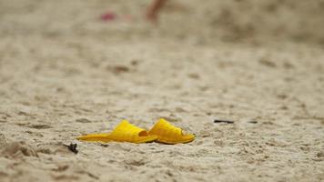 Sandales en plastique jaune sur la plage de sable humide de Nai Harn, Phuket video