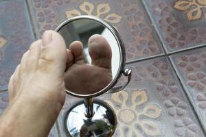 Person looking at the sole of the foot in a mirror. photo