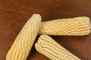 green corn on wooden table without shells photo