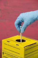 contaminated hospital waste collection box with hand placing a syringe photo