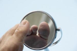 Person looking at the sole of the foot in a mirror. photo