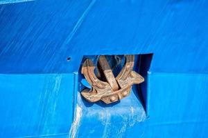 Rusted rugged Anchor on blue fishing ship photo