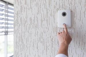 Hand of a man in a white shirt pressing the button of a door photo