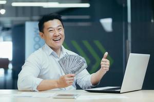 Portrait of happy asian businessman in office with cash money dollars photo