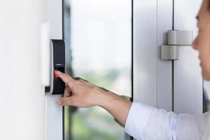 Asian businessman's hand using fingerprint sensor door lock, modern doorbell with video camera photo