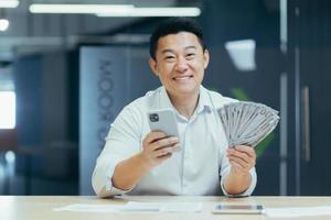 Successful asian businessman working in office, man smiling and looking at camera photo