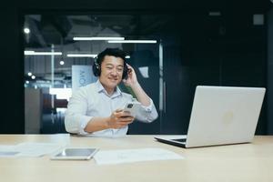 Businessman in office resting during work break, listening to music in big black headphones photo