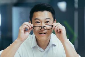 surprised asian man shoots glasses shocked looking at camera. Happy smiling rejoices. photo