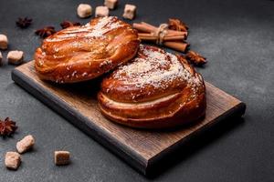 Delicious fresh crispy cinnamon buns sprinkled with coconut crumbs on a wooden cutting board photo