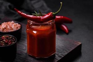 Glass jar with homemade classic spicy tomato pasta or pizza sauce with spices and herbs photo