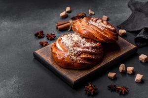 Delicious fresh crispy cinnamon buns sprinkled with coconut crumbs on a wooden cutting board photo