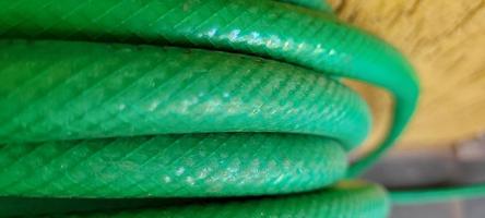 green garden hose rolled up in yard on a sunny day photo