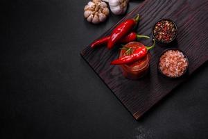 Glass jar with homemade classic spicy tomato pasta or pizza sauce with spices and herbs photo