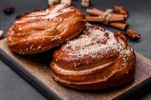 Delicious fresh crispy cinnamon buns sprinkled with coconut crumbs on a wooden cutting board photo