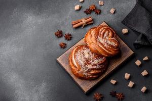 Delicious fresh crispy cinnamon buns sprinkled with coconut crumbs on a wooden cutting board photo
