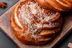 Delicious fresh crispy cinnamon buns sprinkled with coconut crumbs on a wooden cutting board photo