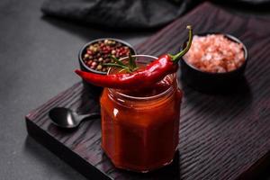 Glass jar with homemade classic spicy tomato pasta or pizza sauce with spices and herbs photo