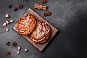 Delicious fresh crispy cinnamon buns sprinkled with coconut crumbs on a wooden cutting board photo