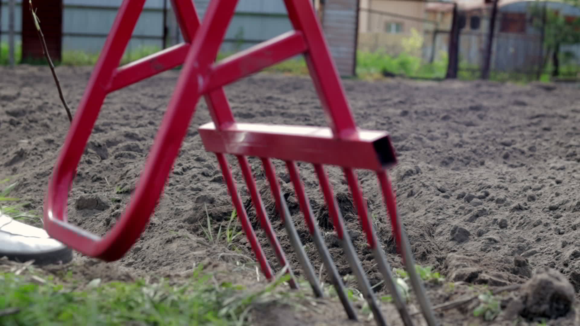 Red shovel in the form of a fork in the garden. Miracle shovel, handy tool. Manual cultivator