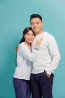 Studio shot of romantic couple posing with smile. Front view of girl and boy hugs on blue background. photo