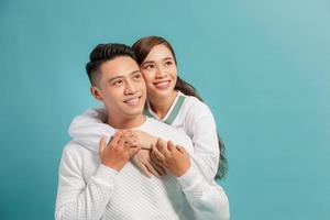 Studio shot of romantic couple posing with smile. Front view of girl and boy hugs on blue background. photo