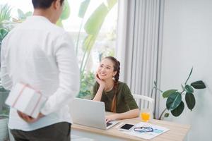 businessman giving gift box to woman in office photo