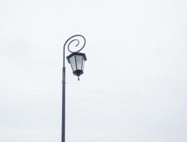 A beautiful street lamp on a background of a gray sky. Patterned lamp shade. photo