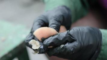 Woman cook peeling potatoes outdoors in the countryside. Stainless steel pot with raw new potatoes. Hands in gloves clean ripe potatoes with a washcloth, the device removes a thin layer of peel. video