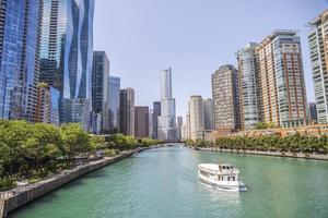 White boat going down a green river through the middle of a city photo