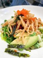 Seaweed salad with fried wontons fish eggs and avocado at a restaurant photo