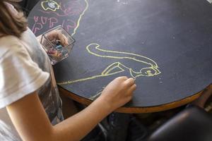 niño dibujando en una mesa de pizarra en un restaurante foto