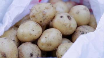 papas frescas jóvenes en una bolsa de celofán blanca limpia. vista superior, endecha plana. el concepto de tiendas de comestibles. video