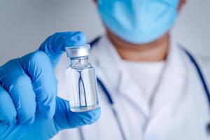 Doctor or researcher Wear blue gloves, work in the laboratory. Pick up a liquid vaccine bottle to treat the coronavirus Or COVID-19. Concept hospital medical services photo