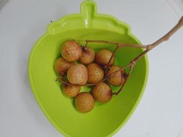 fruta fresca de longan en un tazón verde foto