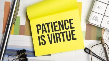 patience is virtue text on the yellow paper with pen and glasses photo