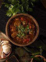 A close up shot of a meat stew and herbs in the background photo
