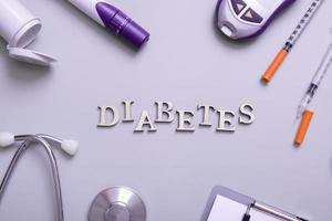 inscripción diabetes y glucómetro, jeringas y equipo médico sobre un fondo coloreado, vista superior foto