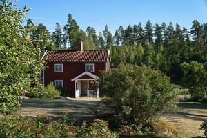 Swedish red and white traditional house in Smalland, White fence green garden blue sky photo