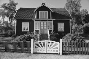 sueco en tiro blanco y negro. casa tradicional en smalland,valla, jardín, cielo foto