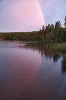 arco iris reflejado en el lago cuando llueve. en el lago cañas y nenúfares. foto