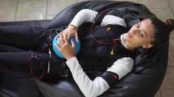 Young woman wears electrodes suit for physical therapy video